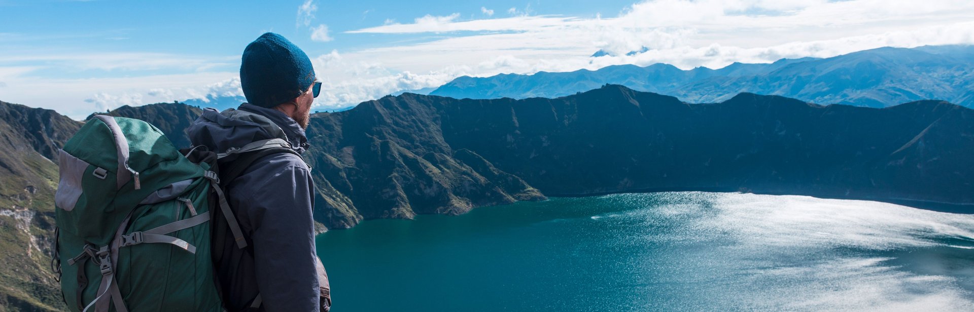 A man looks down on a mountain lake from above